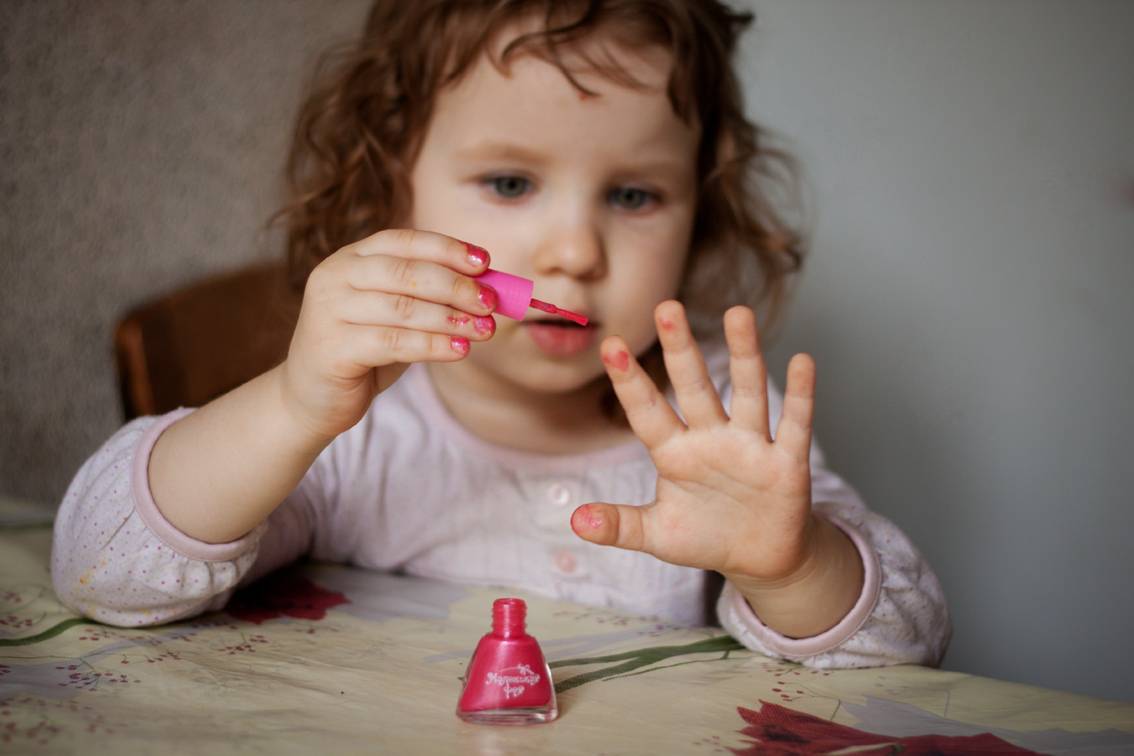 Почему дети красят. Маленькая девочка красит ногти. Детский маникюр. Девочка с накрашенными ногтями. Детские накрашенные ногти.